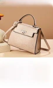 Macro detail of beige crocodile embossed texture and golden metal twist lock on a handbag