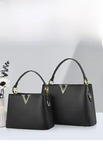 Détail du sac à main noir en cuir grainé avec logo V doré et poignées métalliques rondes