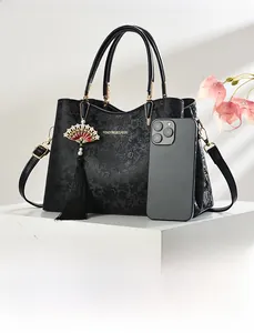 Detail of black floral embossed leather handbag with Chinese fan tassel and gold logo