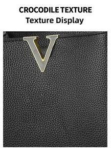 Détail de la texture cuir crocodile noir et de l'emblème métallique V doré sur le sac