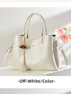 Detail of cream white handbag with floral jacquard, round handles and tassel charm