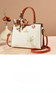 Détail de la broderie de lys élégante sur un sac à main vintage en similicuir blanc