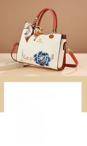 Detail of embroidered blue peony and scrolling patterns on elegant beige handbag