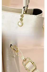 Détail de la poignée renforcée et texture florale en relief sur le sac beige