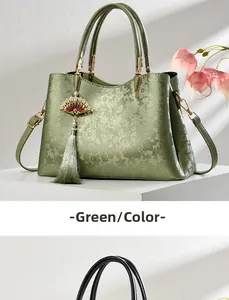 Close-up of green embossed leather handbag with fan tassel and metallic handles