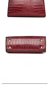 Detailed view of burgundy crocodile pattern handbag showing bottom gold rivets and back panel