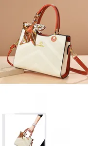 Detail of cream handbag with V-quilted texture, orange handles and silk scarf accent