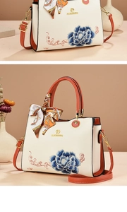 Macro detail of elegant peony embroidery on beige leather handbag with orange handles