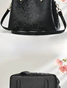 Detailed view of floral embossed pattern and protective metal feet on black handbag