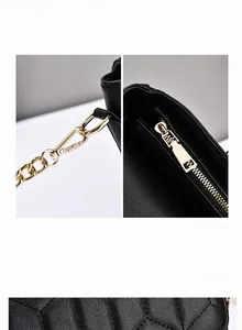 Close-up of golden metal hooks and zipper hardware on black quilted leather crossbody bag