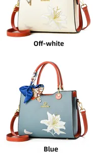 Détails des broderies florales et logo doré sur les sacs à main crème et bleu ciel
