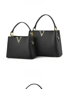 Détail d'un ensemble de sacs en cuir noir avec quincaillerie métallique dorée en V
