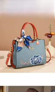 Detail of blue peony embroidery and silk scarf on a contrast handle shoulder bag