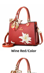 Détail de sac à main rouge vin avec broderie de lys et logo de marque doré élégant