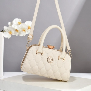 Détail d'un sac à main beige matelassé avec fermoir cristal et logo en métal doré
