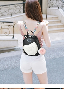 Detail of cute bunny-ear backpack with plush ball charm and colorful printed straps