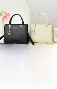 Close-up of leather handbag with gold hardware and heart-shaped crystal pendant detail