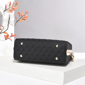 Détail de la base du sac matelassé noir avec pieds en métal doré et motifs de cœurs