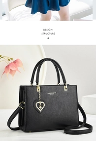 Close-up of black leather handbag featuring lychee texture and golden heart pearl charm
