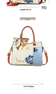 Detailed view of cream handbag with blue peony embroidery and orange top handle