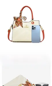 Detailed view of beige embossed handbag capacity with orange handles and silk scarf