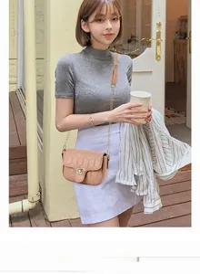 Detail of light beige quilted crossbody bag with gold-tone interlocking buckle and chain strap