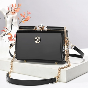 Détail du sac de soirée noir brillant avec logo W doré et fermoir en strass brillant