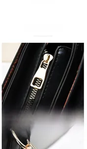 Détail macro de la fermeture éclair en métal doré sur le sac à main en cuir noir
