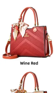 Detail of wine red embossed handbag with gold metal logo and silk scarf on handle
