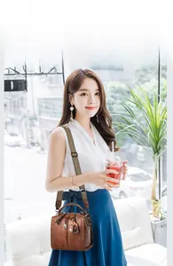 Brown lychee leather boston bag with vintage wavy shoulder strap shown on a model outdoors