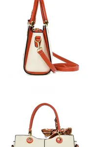 Detail view of contrast leather handbag featuring gold tree charm and decorative silk scarf