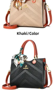 Detail of khaki and black handbags with V-shaped embossing and orange handles