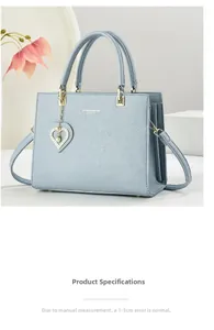 Detail of light blue pebble leather handbag with gold hardware and heart pearl charm