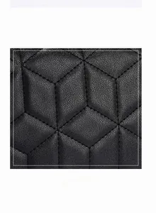 Macro shot of black quilted faux leather fabric with detailed geometric diamond stitching