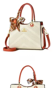 Detail of embossed beige handbag with orange handles and decorative silk scarf accessory