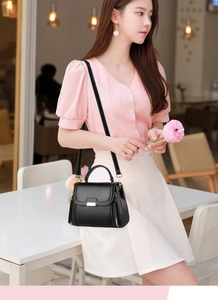 Chic black crossbody bag with gold hardware shown in a stylish cafe setting