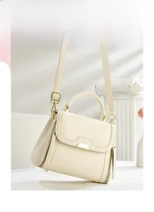 Detail of cream leather crossbody bag with metal plate and decorative side zippers