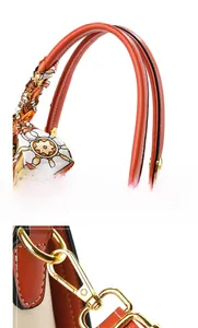 Detail of embossed tote bag featuring orange leather handle and colorful silk scarf wrap