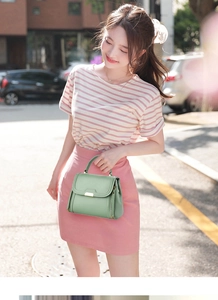 Detail showing a light green leather crossbody bag with metal buckle on a street backdrop