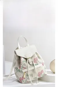 Dettaglio dello zaino in tela ricamata a fiori con patta in pelle bianca e fibbia in metallo