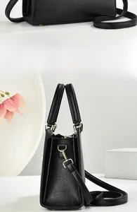 Detail view of black litchi grain handbag showing three-layer gusset structure and strap