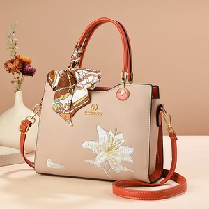 Sac à main beige et orange avec broderie de lys et poignée décorée d'un foulard en soie