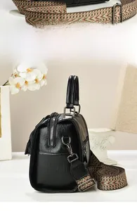 Detail of vintage black Boston bag with colorful ethnic patterned wide shoulder strap
