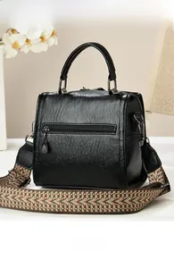 Detail view of black litchi pattern bag with a vintage geometric woven shoulder strap