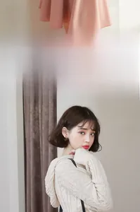 Détail d'un pull à capuche en maille torsadée beige et jupe rose trapèze élégante