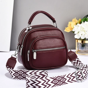 Detailed view of dark red lychee leather tote bag with triple zipper compartments