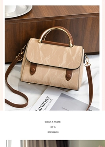 Détail du sac beige marbré avec poignée dorée et finitions en cuir marron