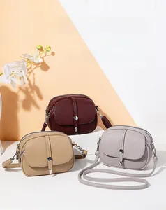 Detailed view of three minimalist lychee grain leather crossbody bags in various colors