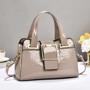Close-up of crocodile pattern leather and large square gold metal buckle on top-handle bag