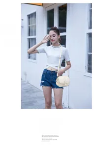 Street style view of a cream small crossbody bag with adjustable strap on a female model